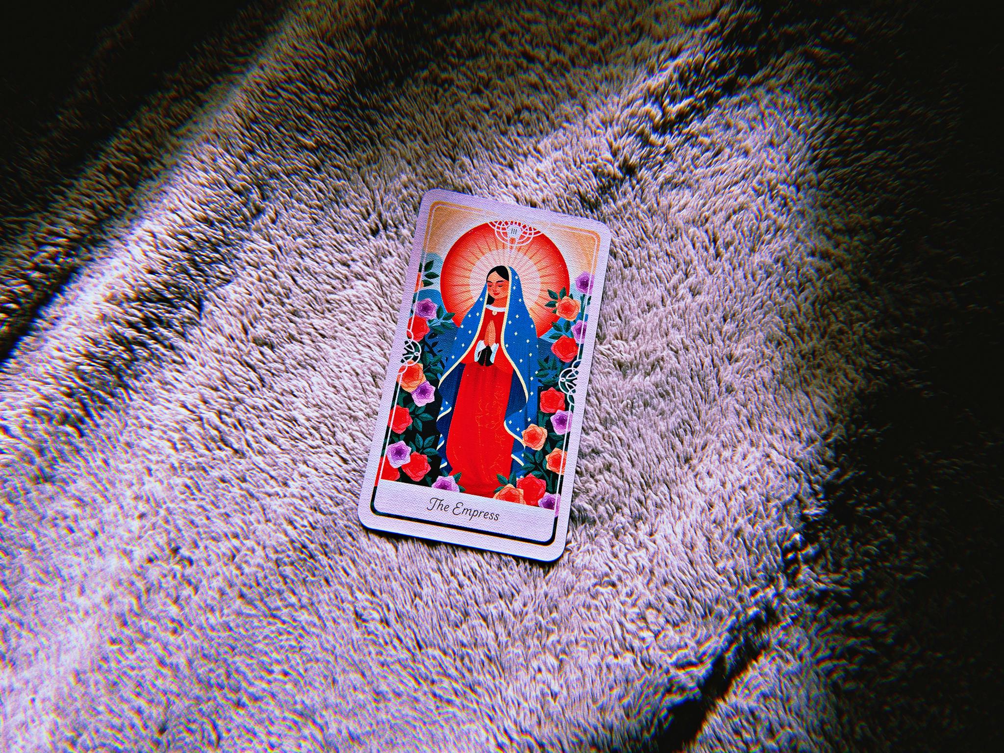 A colorful Empress tarot card lies on a textured surface, evoking mystery.