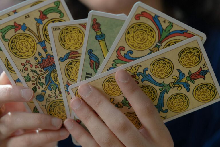 A detailed view of hands holding vibrant Tarot cards, capturing mystical themes.