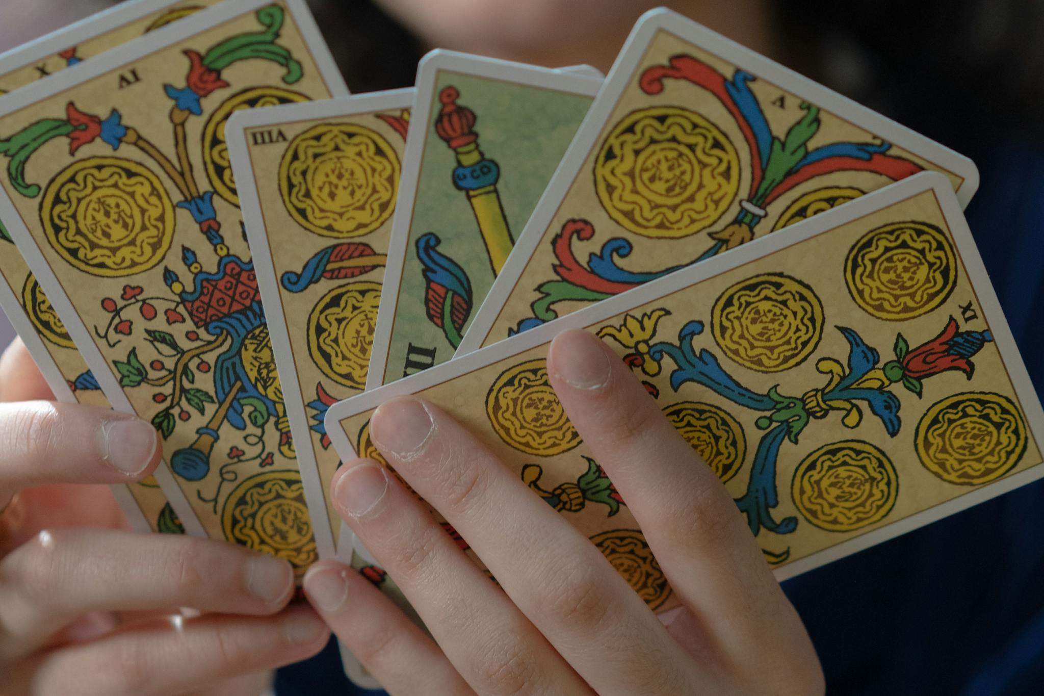 A detailed view of hands holding vibrant Tarot cards, capturing mystical themes.
